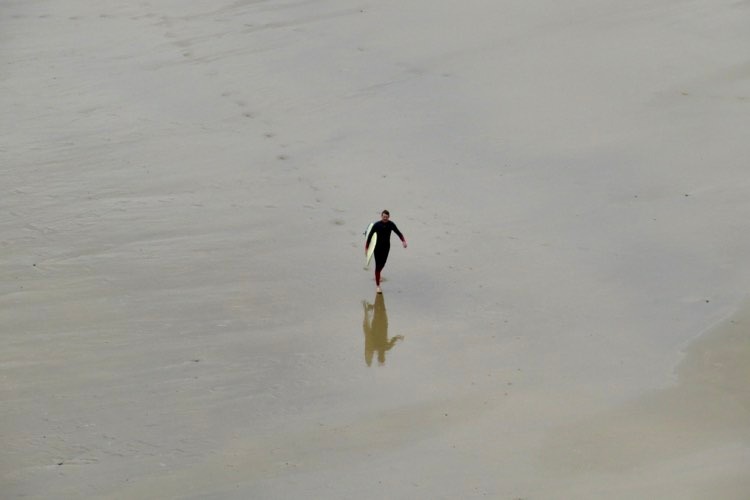 Our surf Guide guest walking back over the beach, stoked with his surf session