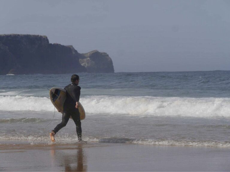 surfer running to the waves surf guide algarve